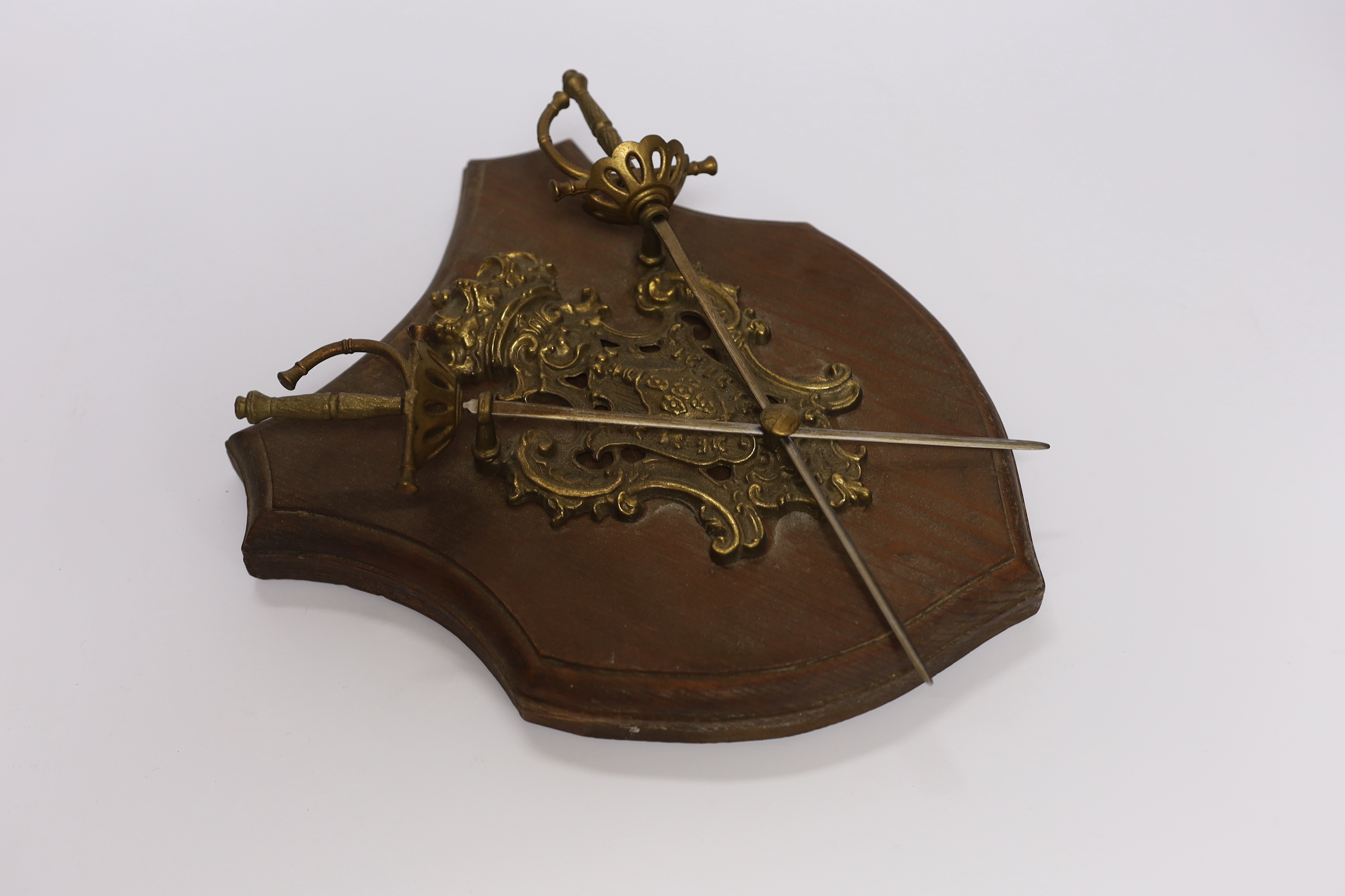 A wall mounting pine ‘shield’ with brass mounts and swords, 28cm